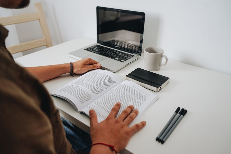 person reading book with laptop open