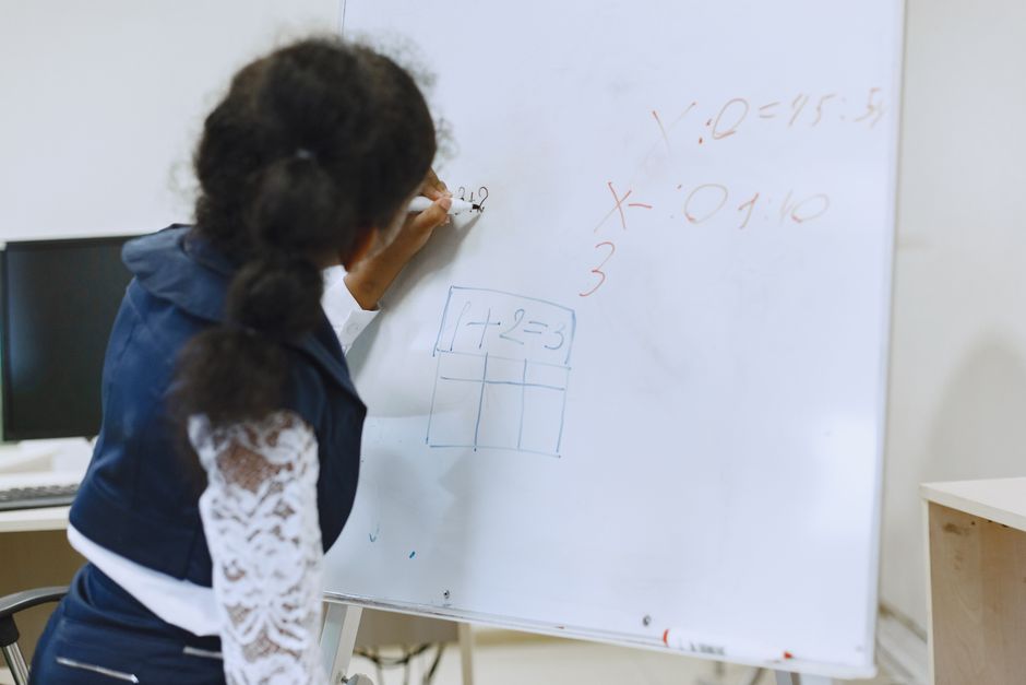 student writing on whiteboard with graphs