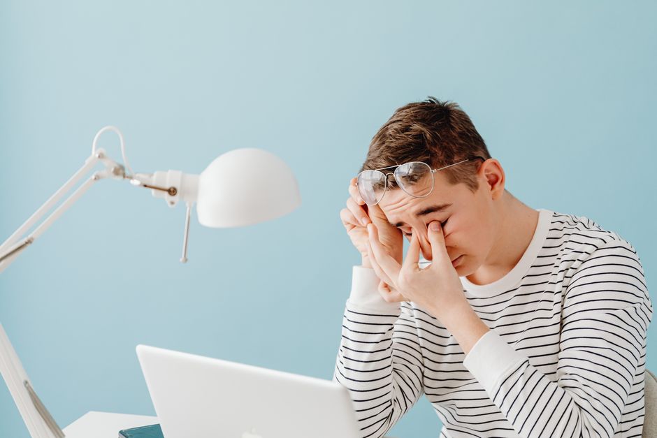 person rubbing eyes at computer screen