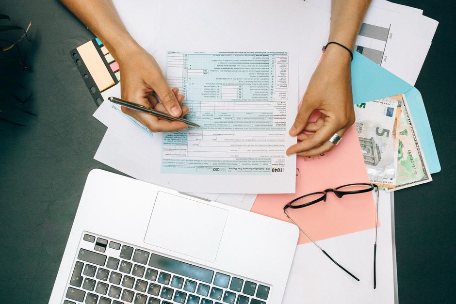 person reviewing documents at desk with laptop