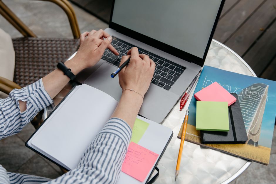 student working at desk with notebook and laptop