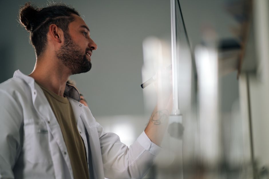 scientist writing on whiteboard with diagram