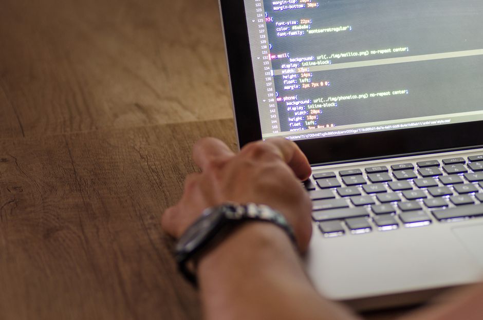 person typing at laptop with code on screen