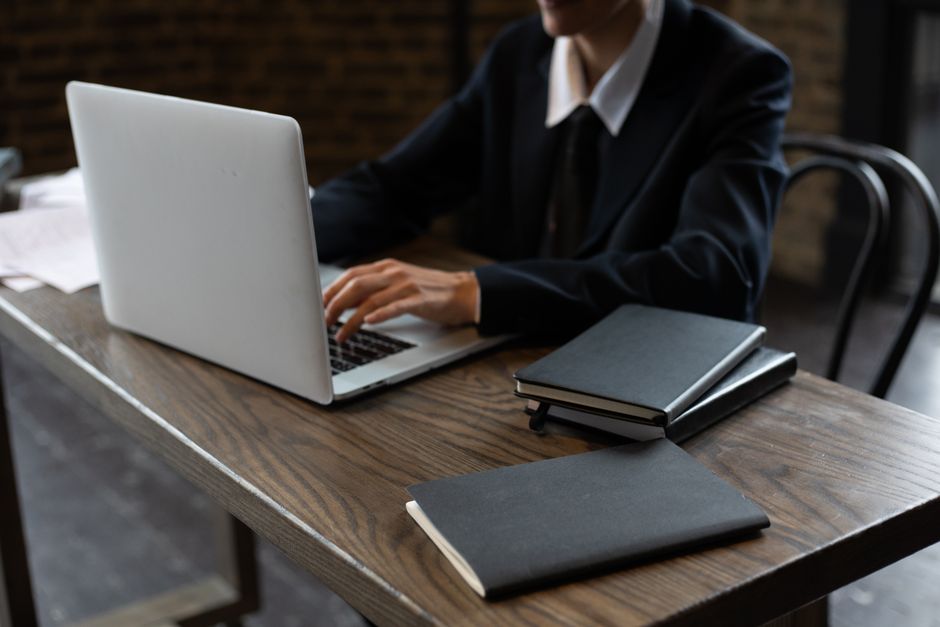 person typing on laptop with notebook